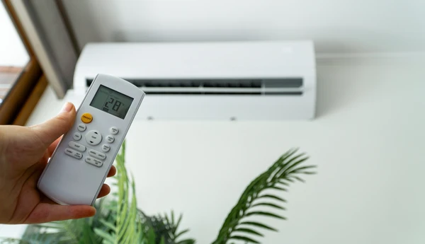 Technicien climaticien professionnel en tenue de travail, équipé d'un presse-papiers et d'outils de diagnostic, effectuant une visite d'étude dans un salon résidentiel. Il est en conversation bienveillante avec le propriétaire des lieux, examinant la pièce et ses caractéristiques (fenêtres, murs, exposition) pour évaluer les besoins en climatisation. L'atmosphère est professionnelle, de confiance, montrant une écoute active et une expertise technique. L'environnement est un intérieur résidentiel moderne et lumineux, typique du bassin marseillais méditerranéen.